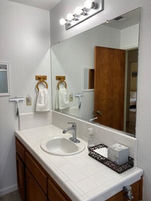 A bathroom with a white sink, a mirror, and a vanity with a wooden cabinet. - Enchanting View, Sequoia/Kings Canyon PKs Getaway (Miramonte)