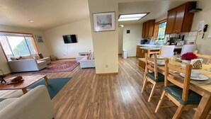 A spacious living area with a wooden floor, a dining table set for four, and a kitchen in the background. - Enchanting View, Sequoia/Kings Canyon PKs Getaway (Miramonte)