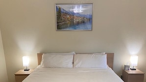 A large bed with white linens, two bedside tables with lamps, and a framed painting above the bed. - Enchanting View, Sequoia/Kings Canyon PKs Getaway (Miramonte)