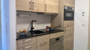 Eine moderne Küche mit Holzausstattung, einer schwarzen Arbeitsplatte, einem Bosch-Ofen und einer eingebauten Mikrowelle.
