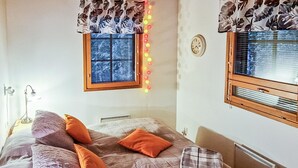 A bedroom with a bed, a window with blinds, a wall clock, and a radiator. - Alppitalo sinitähti 9 as 3 by Interhome (Nilsiä)