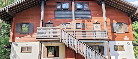 Un edificio de madera de varios pisos con balcones, una escalera y asientos al aire libre.