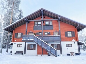 A two-story lodge with a wooden facade, a balcony, and a staircase leading to the upper floor. - Alppitalo sinitähti 9 as 3 by Interhome (Nilsiä)