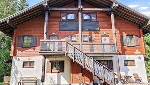 A two-story wooden building with a balcony, a staircase, and a bench outside. - Alppitalo sinitähti 9 as 3 by Interhome (Nilsiä)