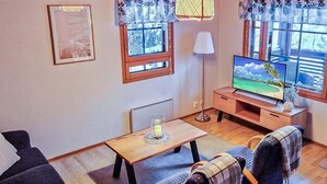 A cozy living room with a sofa, two armchairs, a coffee table, a TV, and a window with a view. - Alppitalo sinitähti 9 as 3 by Interhome (Nilsiä)