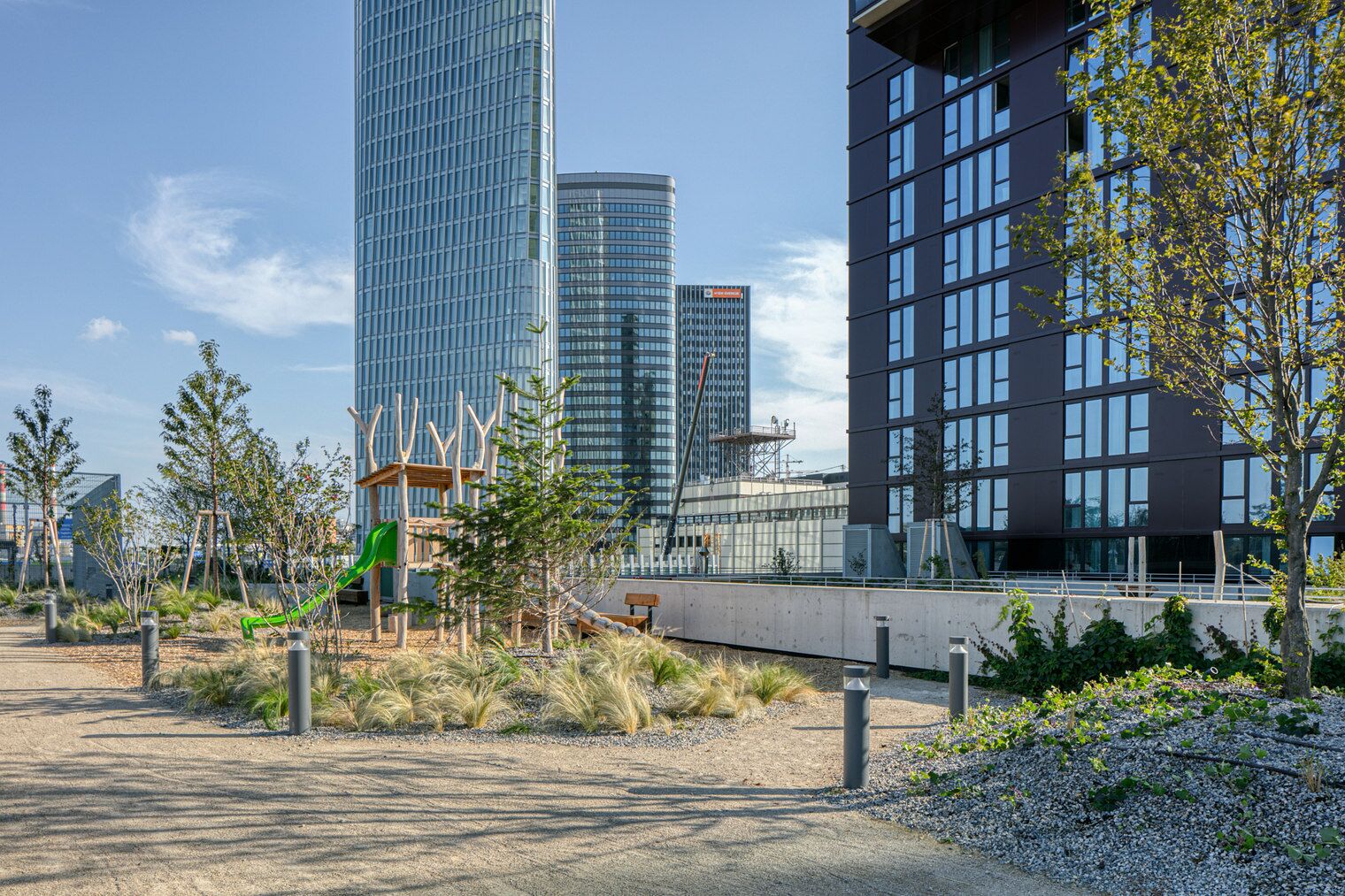 Ein moderner Stadtpark mit Spielgeräten, umgeben von Hochhäusern.