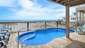 A wooden deck with a swimming pool, deck chairs, and a view of the beach. - Beachfront | Pet Friendly | Heated Pool (Gulf Shores)
