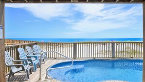 A wooden deck with a pool and beach chairs, overlooking a sandy beach and ocean. - Beachfront | Pet Friendly | Heated Pool (Gulf Shores)