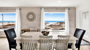 A dining area with a view of the beach, a wooden table, and chairs. - Gulf Views | Private Heated Pool | Pet Friendly (Gulf Shores)