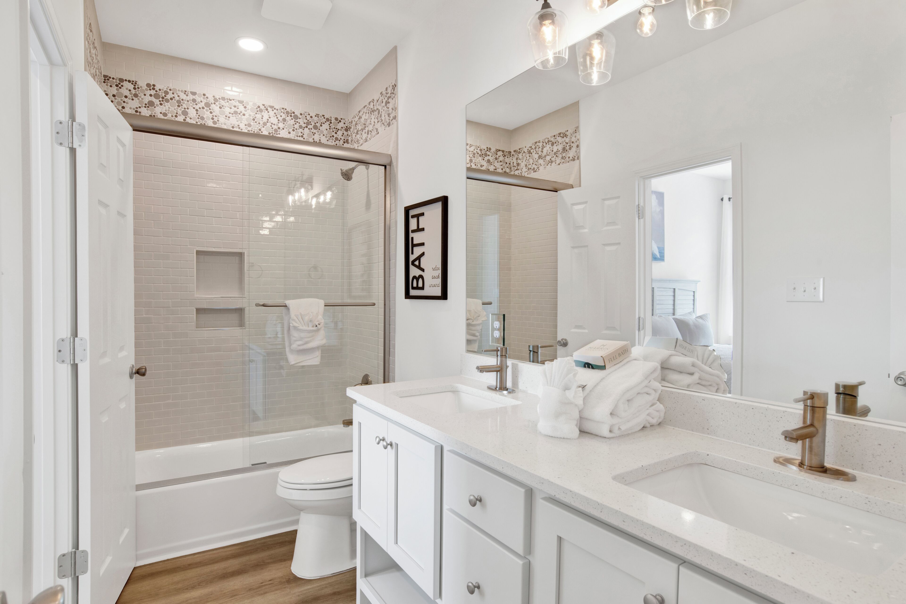 A modern bathroom with a glass-enclosed shower, a white sink, and a large mirror.