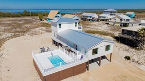 A beachfront property with a swimming pool, multiple buildings, and a view of the ocean. - Gulf Views | Private Heated Pool | Pet Friendly (Gulf Shores)