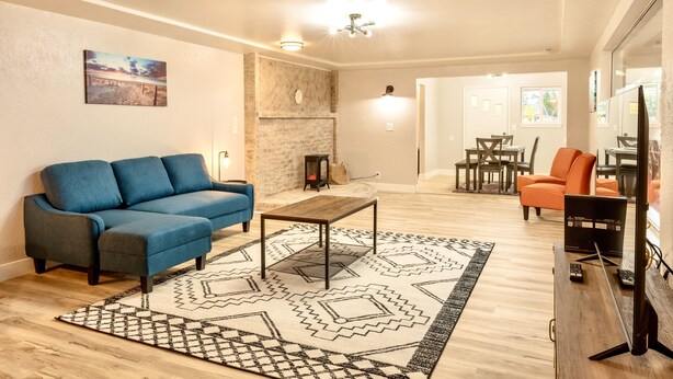 Un salon avec un canapé bleu, une table basse en bois et un tapis à motifs.
