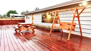 Une terrasse en bois avec une balançoire et une table de pique-nique.