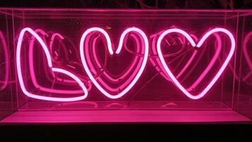 En neonskylt med ordet ”LOVE” skrivet med rosa neonljus, placerad inuti en genomskinlig akrylbox.