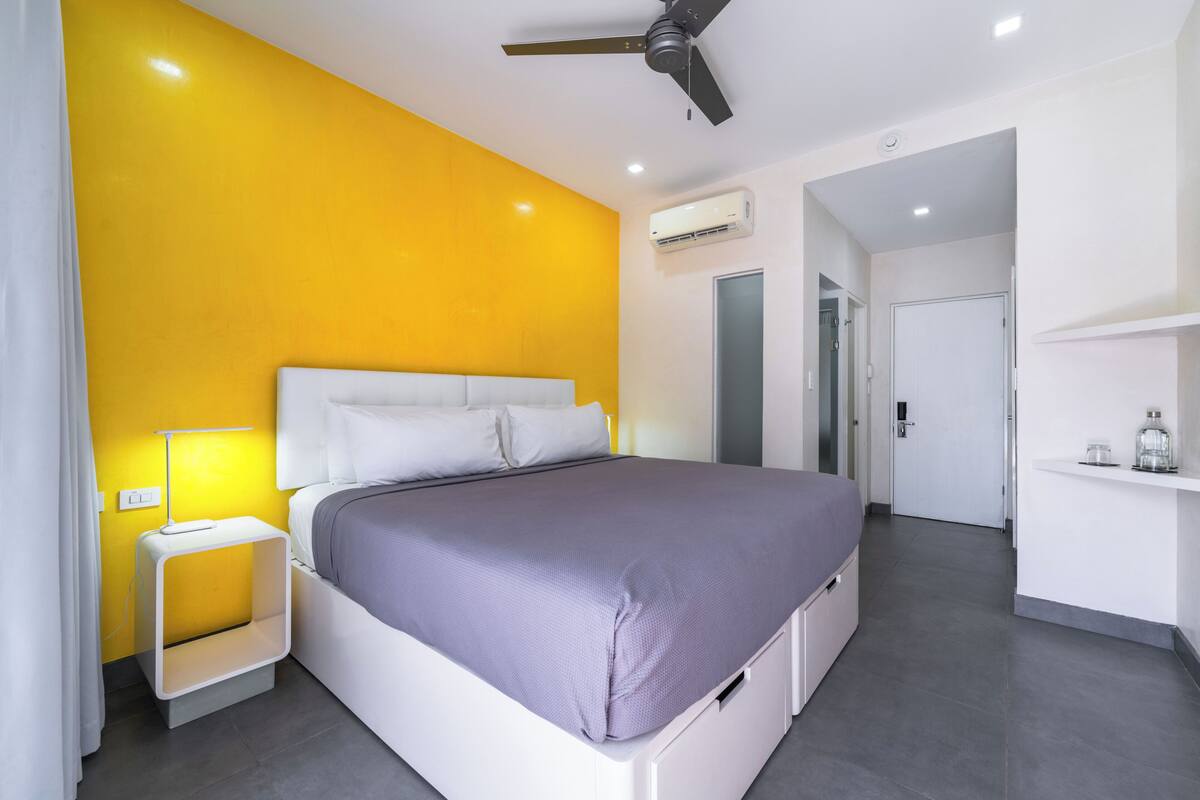 A modern bedroom with a bed, bedside table, and a ceiling fan.