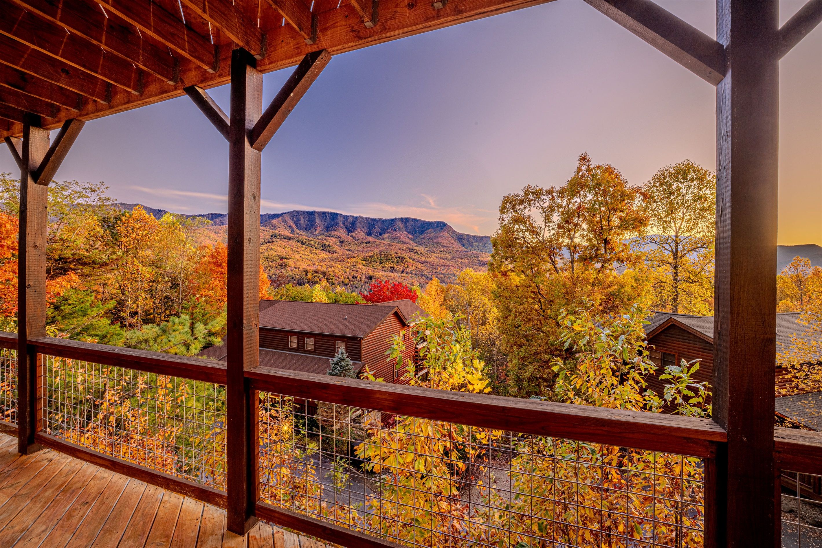 Una terraza de madera con vistas al follaje otoñal y montañas.