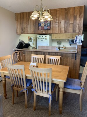 A kitchen with wooden cabinets, a central island, and a dining table with chairs.
