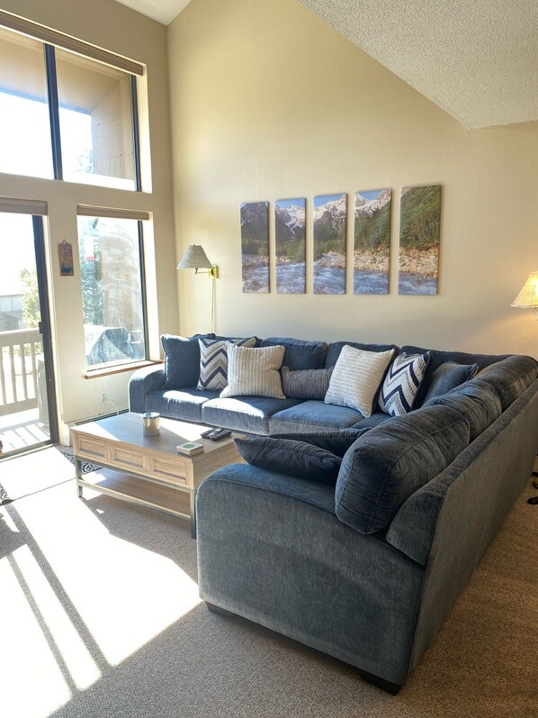 A living room with a blue sofa, a coffee table, and a lamp. There are four framed pictures on the wall.