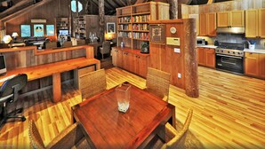 Ein rustikaler Innenraum aus Holz mit Essbereich, Bücherregalen und einer Küche.