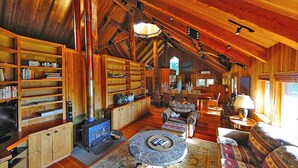 Ein gemütliches Blockhaus-Interieur mit Holzregalen, einem Kamin, einem runden Couchtisch und einer komfortablen Sitzecke.