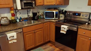Una cocina con armarios de madera, electrodomésticos de acero inoxidable y encimera de granito.