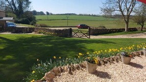 A rural landscape with a stone wall, a red car parked near a gate, and a field in the background. - Large Static Motorhome-Stunning Countryside Views (Cirencester)