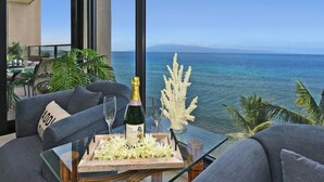 Un balcon avec vue sur l’océan, une bouteille de champagne et un plateau de fleurs.