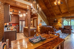 A rustic cabin interior with a kitchen, dining area, and a loft bedroom.