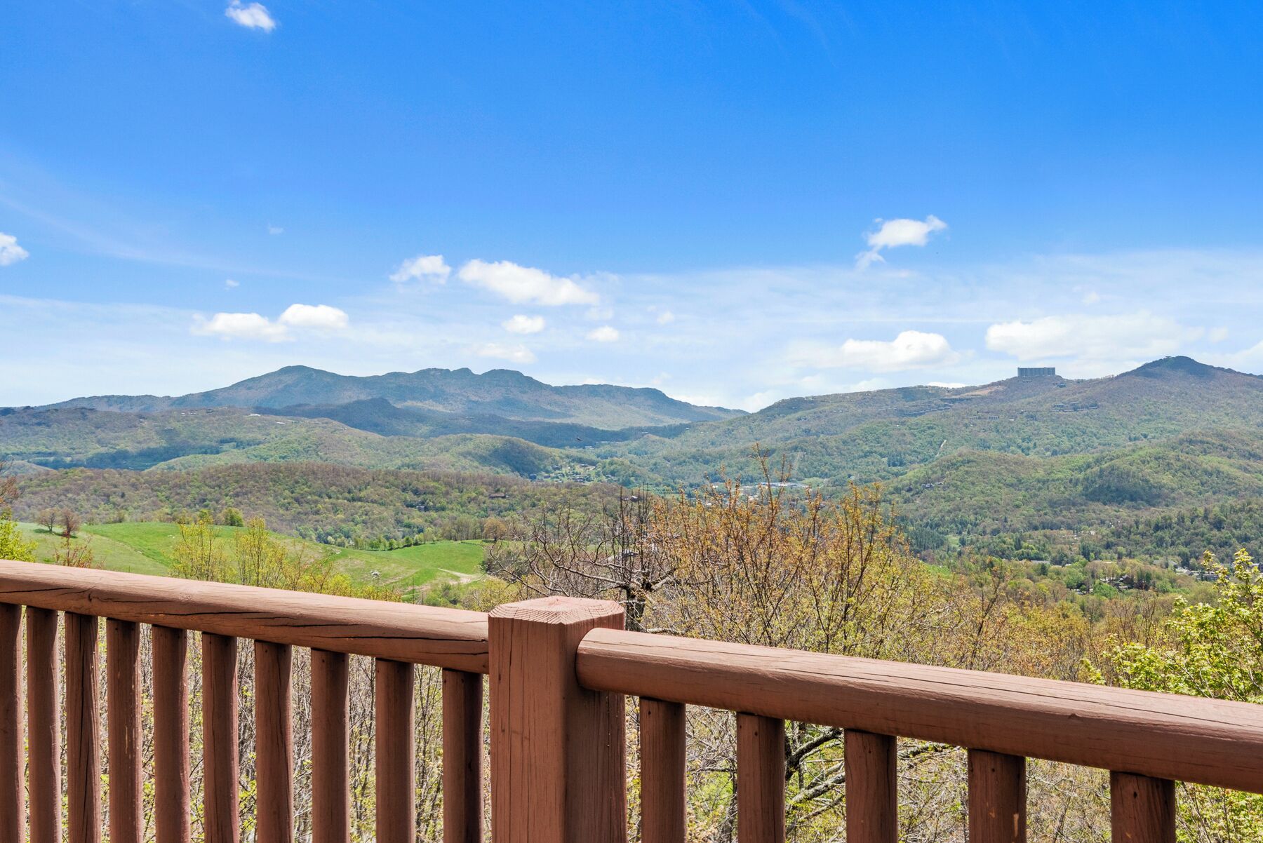 Une terrasse en bois offrant une vue sur un paysage montagneux sous un ciel dégagé.