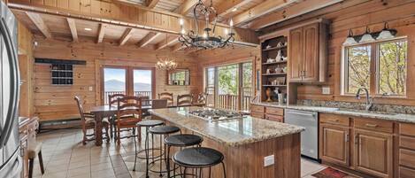 Una cocina amplia con una isla grande, armarios de madera y vistas al exterior.