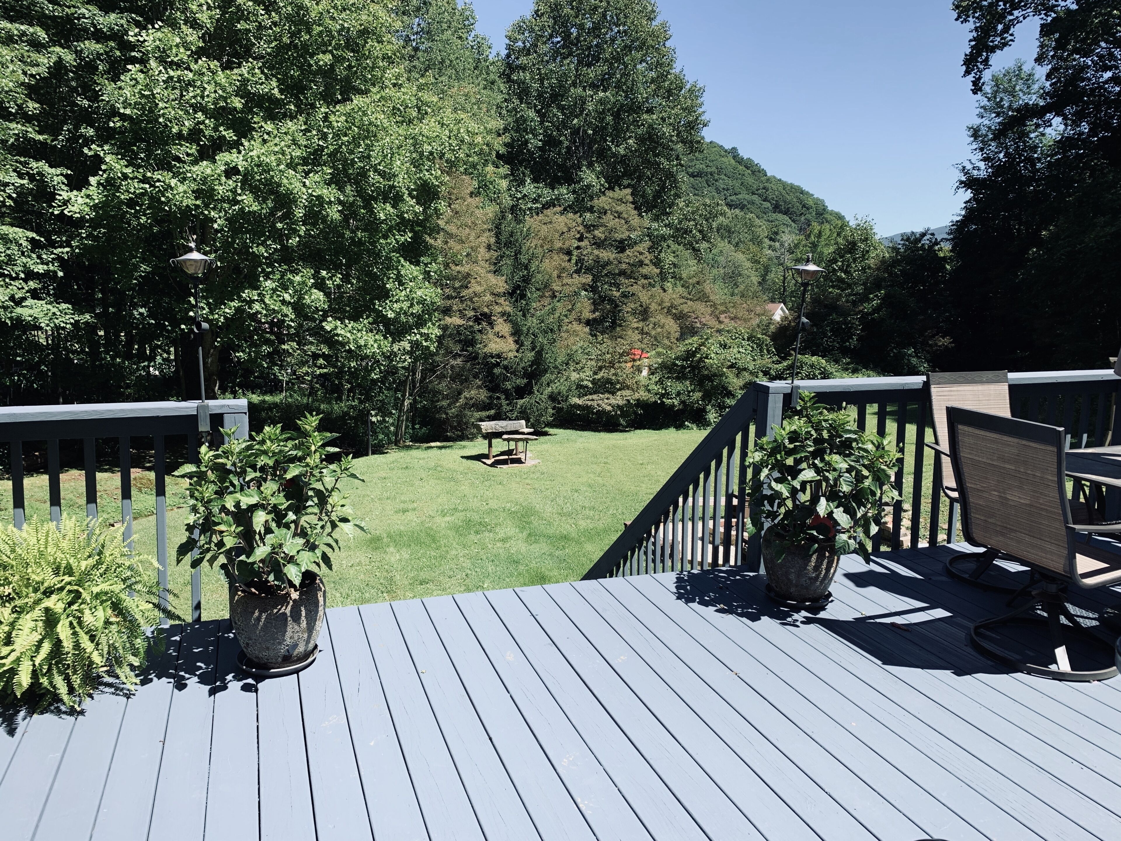 A deck with a view of a grassy yard and trees.