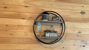 A wooden table with a vase of dried flowers, a metal shelf with decorative items, and a wall with a motivational sign. - Cozy, romantic cabin in beautiful Roan Mt Tennessee & hot tub (Roan Mountain)