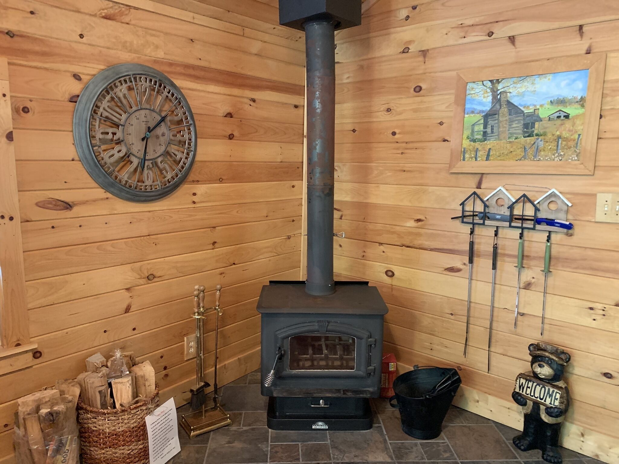 Interno di un rustico chalet con stufa a legna, orologio e decorazione a tema orso accogliente.