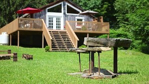 A rustic cabin with a wooden deck and a stone bench in front. - Cozy, romantic cabin in beautiful Roan Mt Tennessee & hot tub (Roan Mountain)