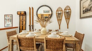 Un comedor con una mesa de madera dispuesta para cuatro personas, rodeado de sillas tejidas.