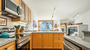 Una cocina moderna con armarios de madera, encimeras de granito y electrodomésticos de acero inoxidable.