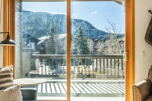 A room with a large sliding glass door leading to a balcony with a view of mountains and trees. - Snowcreek Spa Golf 2BR Condo 530 (Mammoth Lakes)