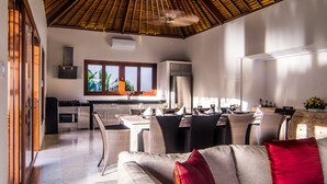 Una cocina moderna con un ventanal grande, comedor con mobiliario de mimbre y un ventilador de techo.