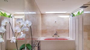 Un baño moderno con bañera, plantas de orquídea y una cabina de ducha de vidrio.