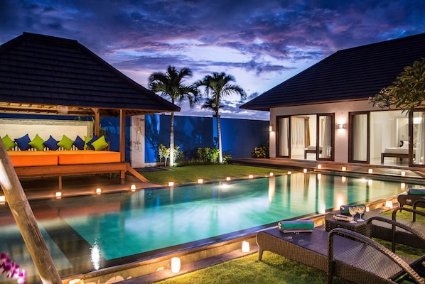 Relax by the serene pool surrounded by lush greenery and comfortable seating.