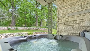 Un jacuzzi con un muro de piedra de fondo, rodeado por un muro de contención de piedra y follaje.