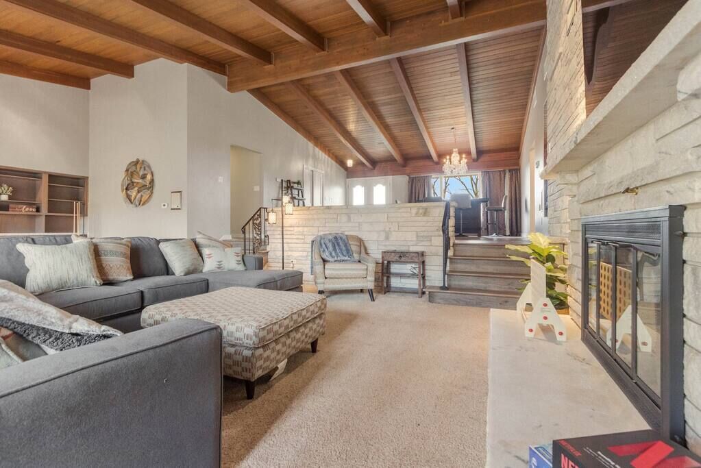 A spacious living area with a fireplace, a sofa set, and a stone wall.