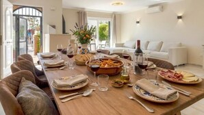 A dining area with a wooden table set for a meal, surrounded by sofas and a modern chandelier. - 2 Beautiful Beach Front Villa in Mijas Playa Club (La Cala de Mijas)