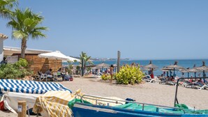 A beach with umbrellas, lounge chairs, and a blue boat with the number 5-01-00. - 2 Beautiful Beach Front Villa in Mijas Playa Club (La Cala de Mijas)