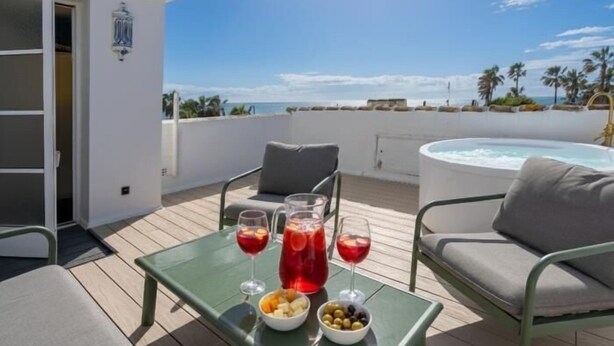 A terrace with a table set for two, a hot tub, and a view of the sea. - 2 Beautiful Beach Front Villa in Mijas Playa Club (La Cala de Mijas)