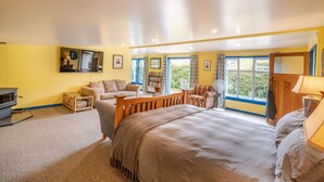 A spacious bedroom with a large bed, a sofa, a wooden coffee table, and a bookshelf.