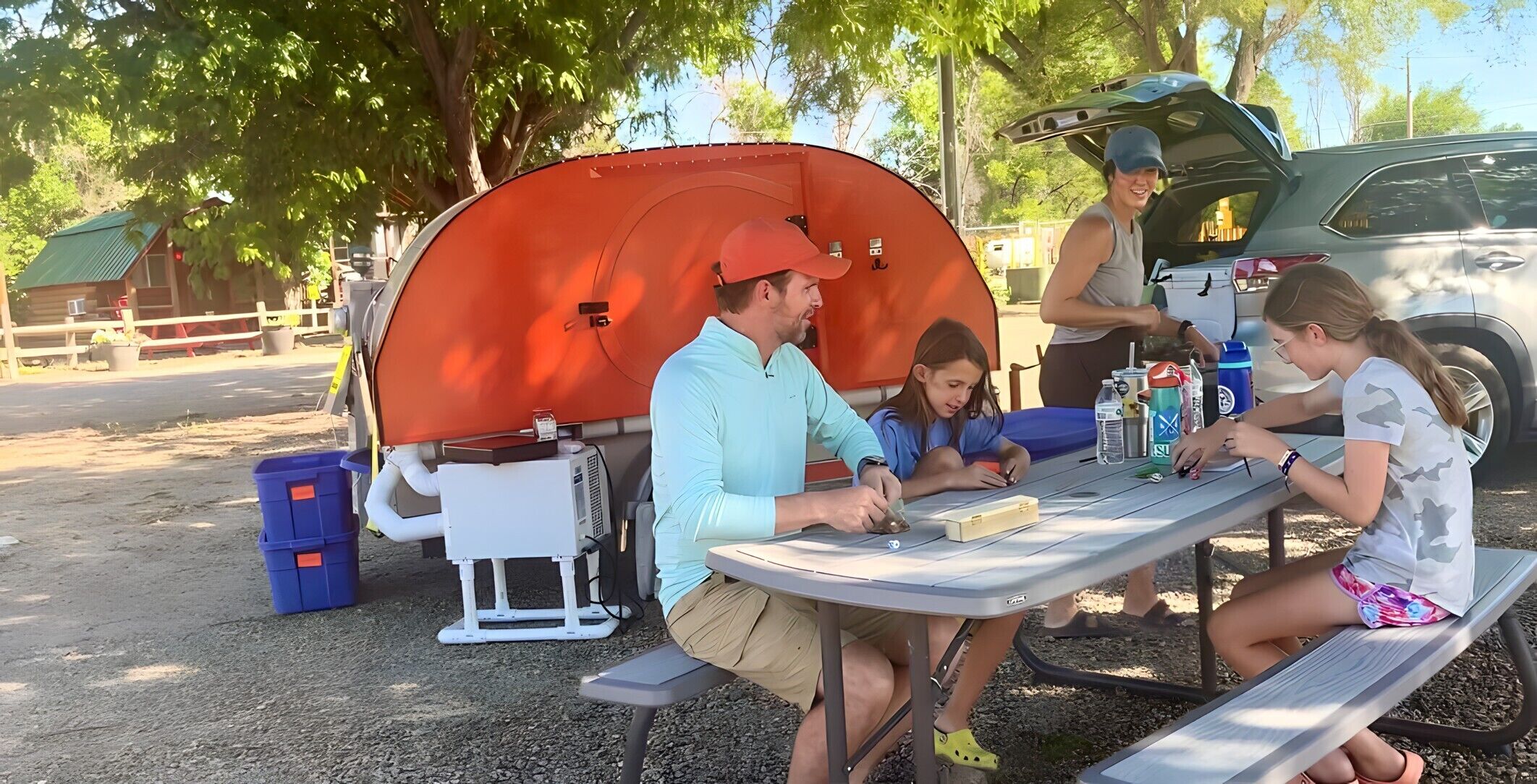 Una familia acampando con una carpa portátil y una mesa de picnic.