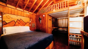 A wooden cabin interior with a bunk bed, a small kitchenette, and a wooden ceiling. - La Junta Camping & Cabins (La Junta)