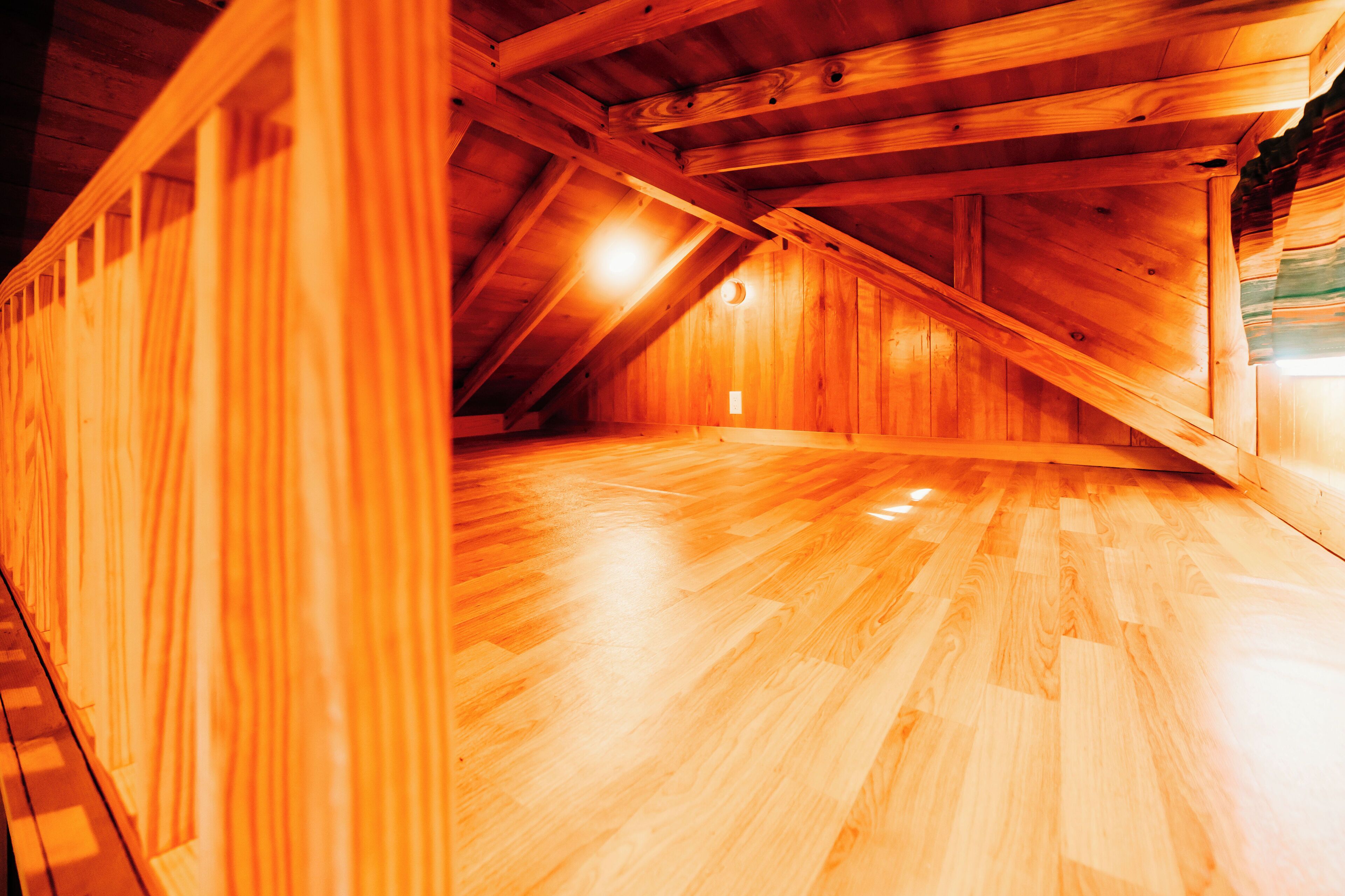Une chambre mansardée avec un plancher en bois et des plafonds inclinés.