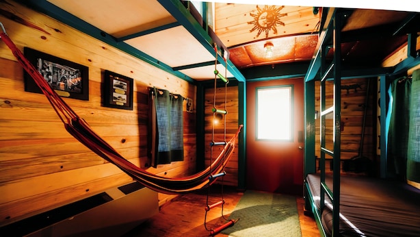 A wooden cabin interior with a hammock, wooden walls, a window, and a door. - La Junta Camping & Cabins (La Junta)